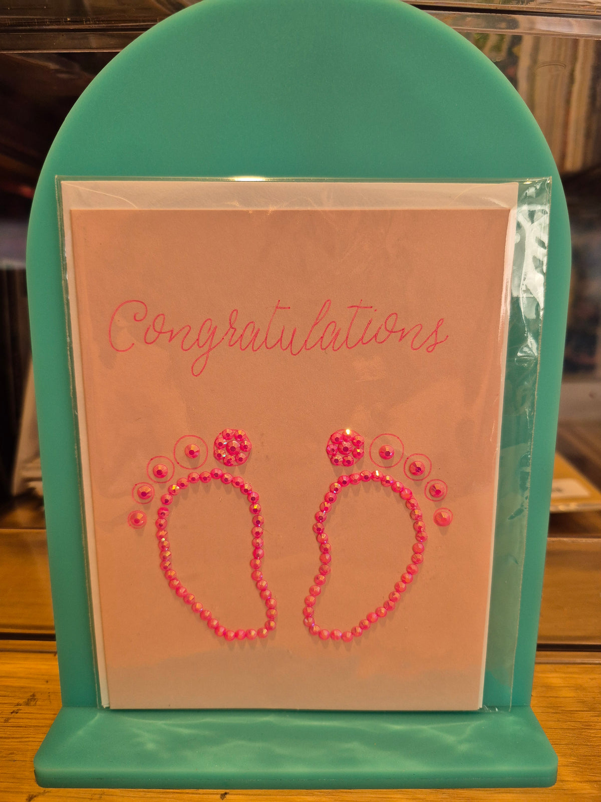 Baby congratulations card with two pink sparkling footprints and Congratulations lettering