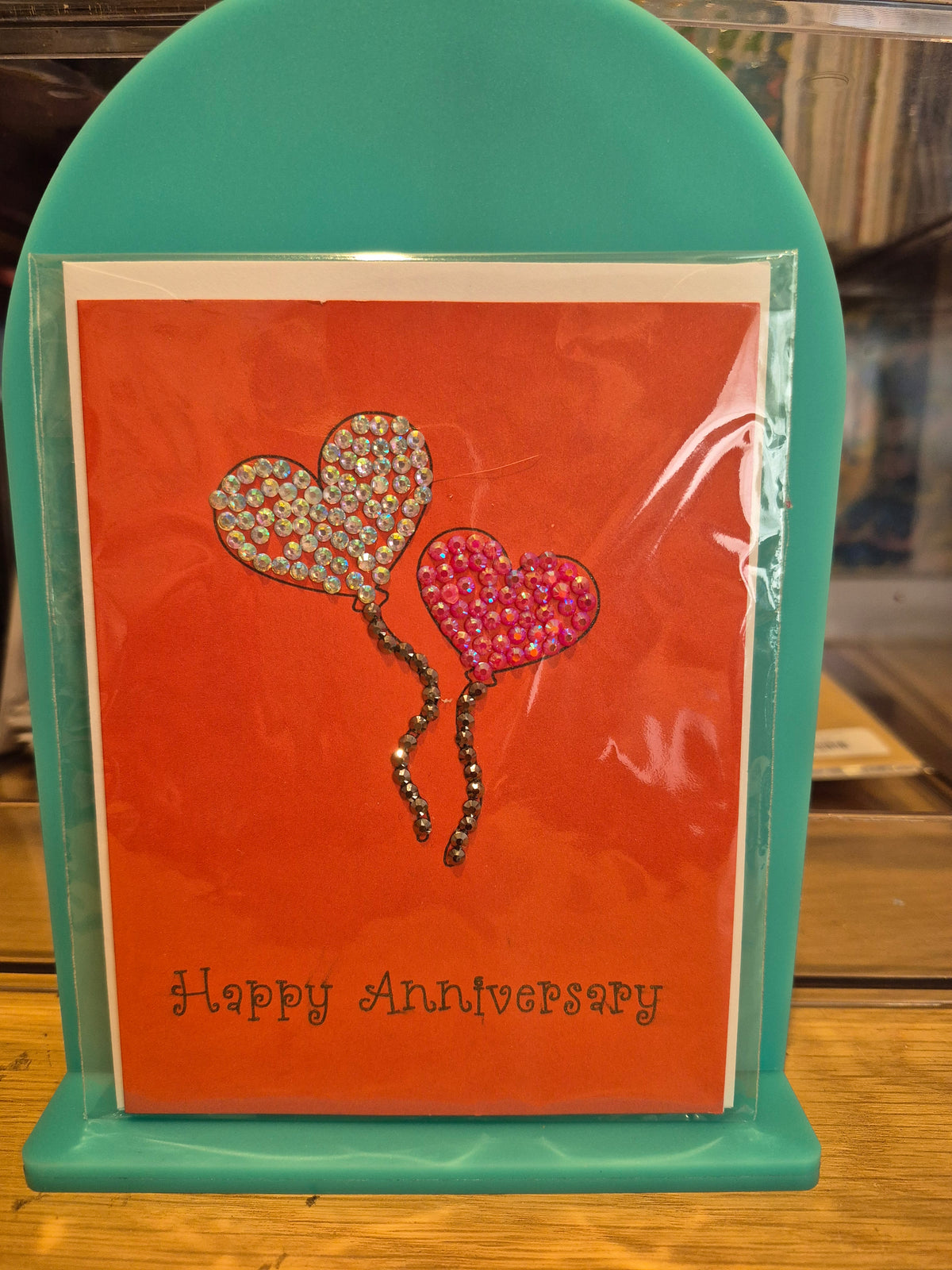 Red anniversary card with silver and pink sparkling heart balloons and Happy Anniversary lettering